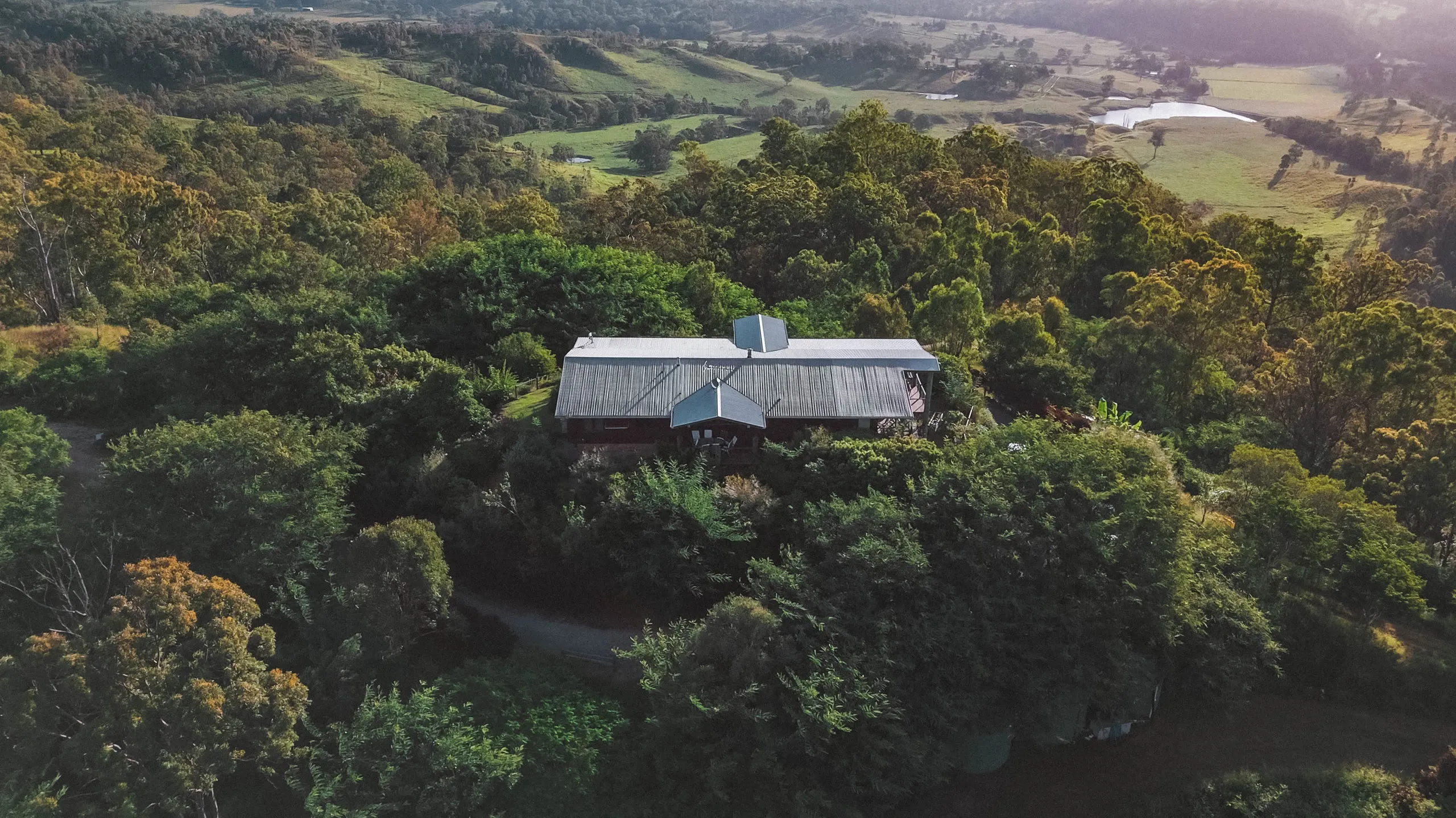 The house set into its hillside on the ridgeline, Sarabah Valley beyond